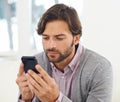 Connected to the world. A handsome young man looking at his cellphone. Royalty Free Stock Photo