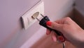 Connecting black electric plug with hand to white plastic socket on awhite wall Royalty Free Stock Photo