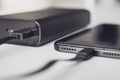 Connecting your phone to a portable charger, close-up. The Power bank and the smartphone are connected by a cable and lie on a