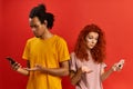 Connection error. Black millennial man and redhead woman looking at smartphones, annoyed with discharged or broken