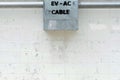 A connector box of a cable EV car charger on the cement wall of the frence