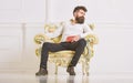 Connoisseur of literature concept. Macho spends leisure with book. Man with beard and mustache sits on armchair and