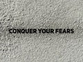 CONQUER YOUR FEARS text on concrete background. Inspirational and motivational concept. Stock photo.