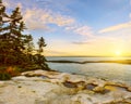 The conquest of the Atlantic Ocean. Rocky shore and cold trees on a cliff at sunset. Maine. USA. Reid National Park. Royalty Free Stock Photo