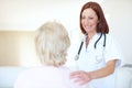 A conscientious checkup on an adored patient. Friendly mature nurse comforts her elderly patient with a hand to the