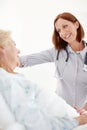 Conscientious healthcare for the elderly. Mature doctor pays her elderly female patient a visit following an operation.