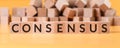 Consensus word on wooden cubes on yellow background with blurred cubes