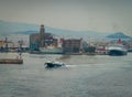 Conseptual shot of the ship that is leaving the port the other ships and the command tower ,in a cloudy day with calm sea Royalty Free Stock Photo