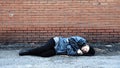Bearded homeless lies down on ground to sleep. Tramp in dirty clothes, hat cap. Below poverty line. Fugitive beggar. Illegal Royalty Free Stock Photo