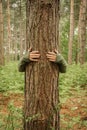 A tree hugger wrapping his arms around a tree trunk in a conservation and ecology image