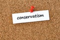 Conservatism. Word written on a piece of paper, cork board background Royalty Free Stock Photo