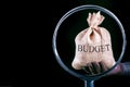 Consider the budget through a magnifying glass close up. Bag with money-budget under magnifying glass. Royalty Free Stock Photo