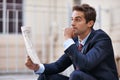 Considering stock options. a handsome businessman reading the stock pages outside. Royalty Free Stock Photo