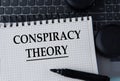 CONSPIRACY THEORY - words on a white sheet on the background of a computer keyboard and headphones