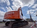 Constructing Progress: Hitachi Excavator and Workers on a Busy Street