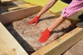 Constructing a rooftop a building contractor in protective gloves is lying glass wool batt insulation Royalty Free Stock Photo