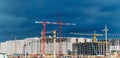 Construction of apartment buildings under a blue sky. Cranes on the construction of concrete houses