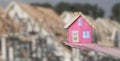 Construction and architecture concept. Cute model home on a female hand on blurred building shell and conctruction site Royalty Free Stock Photo