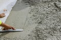 In the construction area, a worker is holding a steel trowel to smooth leveling over freshly poured concrete sidewalks Royalty Free Stock Photo