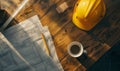 A construction blueprint is on a wooden table. A yellow hard hat and a coffee cup Royalty Free Stock Photo