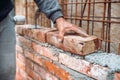 Bricklayer placing and adjusting bricks with mortar. Professional construction worker building exterior walls