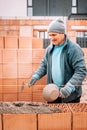 Construction bricklayer worker building house walls with bricks, mortar and rubber hammer