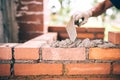 Construction bricklayer worker building walls with bricks, mortar and putty knife