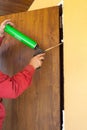 Construction builder works with polyurethane foam during frame insulation at door installation.