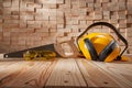 Construction Carpentry Concept. Yellow Safety Goggles Helmet And Earphones. Classic Handsaw With Wooden Handle On Background Wood