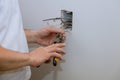 Construction in close-up of electricians hand installing outlet on wall with using professional tools