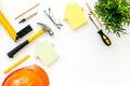 Construction concept. Helmet, tools on work desk, house cutout on white background top-down frame copy space