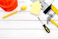 Construction concept. Helmet, tools on work desk, house cutout on white wooden background top-down frame copy space Royalty Free Stock Photo