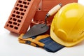 Stack of bricks with masonry trowel, construction hard hat and gloves on white background. Construction concept