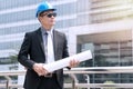 Construction concept. Success Engineer blue helmet for safety and checking building plans. Young businessman wear sunglasses