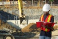 Construction contractor on site reading papers shovel