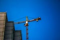 Construction crane against the blue sky. The real estate industry. A crane uses lifting equipment at a construction site Royalty Free Stock Photo