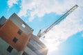 Construction crane builds a house in the afternoon Royalty Free Stock Photo