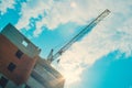 Construction crane builds a house in the afternoon Royalty Free Stock Photo