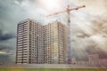 Construction crane builds multi-apartment residential house.