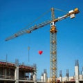 Construction crane and heart-shaped balloon. Royalty Free Stock Photo