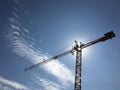 Construction crane silhouette with sun in blue sky with clouds Royalty Free Stock Photo