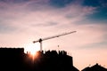 Construction crane on site with silhouette of building and workers Royalty Free Stock Photo