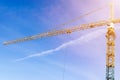 Construction crane tower on background of blue sky. Crane and building working progress. Yellow lifting faucet. Empty Space for te