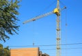 Construction crane tower on blue sky background. Crane and building working progress. Yellow lifting faucet. Empty Space for text Royalty Free Stock Photo