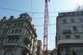 A construction crane among two historical building in Zurich, Bahnhofstrasse, on one of therm there is Glockenspiel, playing bells