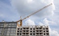 Construction crane on an unfinished residential building against the sun and blue sky. Housing construction, apartment building in Royalty Free Stock Photo