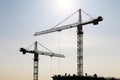 Silhouette of construction crane and workers on unfinished residential building against sunshine