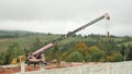 Construction crane working on building in mountains landscape. Loading crane working on construction site. Real estate. Constructi