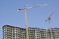 Construction cranes on the background of the building under construction and the sky Royalty Free Stock Photo