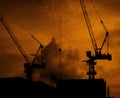 Construction cranes on high-rise building with dramatic orange sky and clouds at sunset time in the evening. Construction site Royalty Free Stock Photo